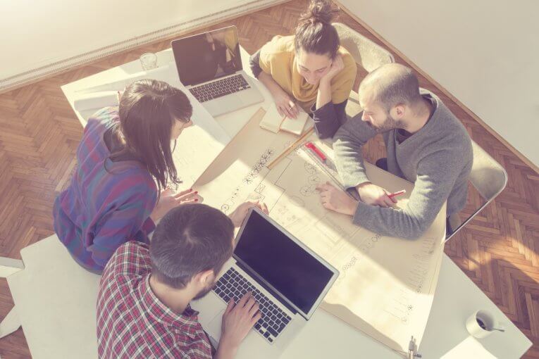 Wirtschaftsinformatik studieren Infos Erfahrungsberichte Vier Studentinnen und Studenten sitzen um einen Tisch und diskutieren