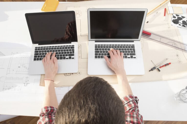 Wirtschaftsinformatik studieren Infos duales Studium Student sitzt an zwei Laptops gleichzeitig